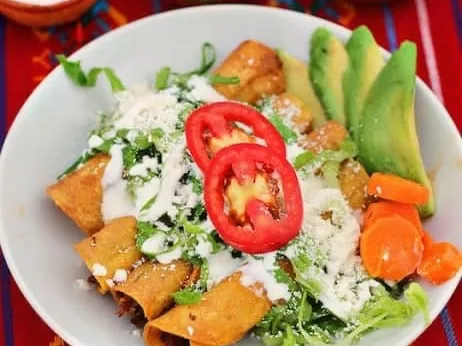Flautas de pollo con crema, queso, aguacate y ensalada